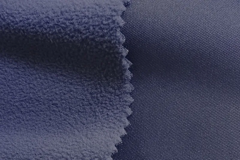 Brushed fleece backing laminated to a navy face fabric — the raised inner layer of fleece-backed bonded fabric